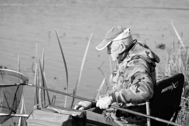 Strategic Patience, elderly man fishing in tranquil lake setting